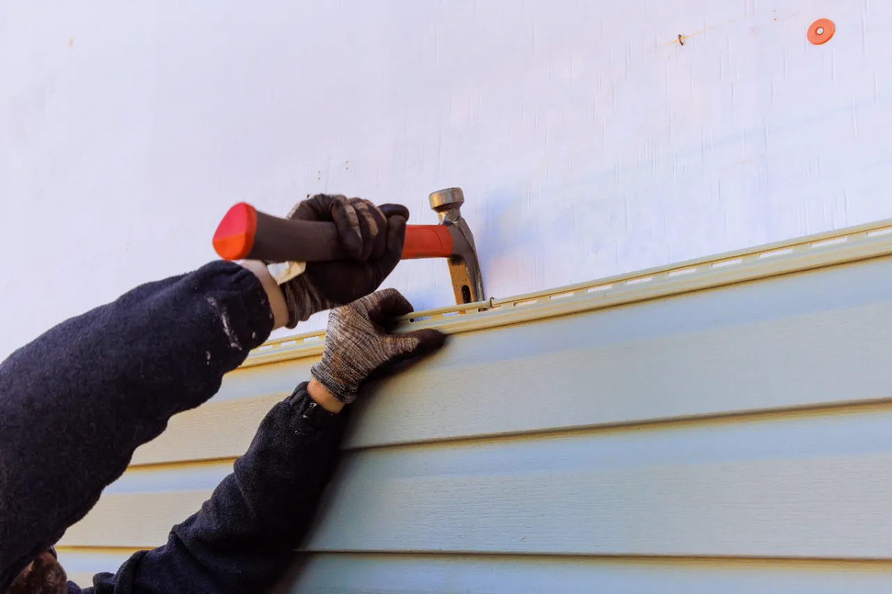Hammering vinyl siding on exterior wall
